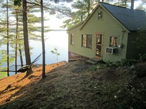 a small green house on a hill near the water at Gorgeous, Lakefront Vacation Rental in the Charming Town of Wayne in Central Maine in Wayne