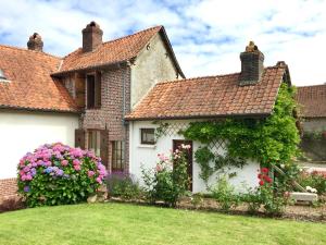 una casa blanca con flores en el patio en Gîte Margot, en Vacqueriette