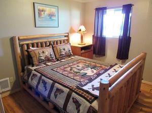 a bedroom with a wooden bed with a quilt on it at Magnificent Log Cabin with Mountain Views near Yellowstone National Park, Montana in Cliff Lake