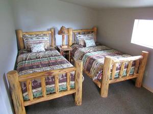 a bedroom with two twin beds and a lamp at Magnificent Log Cabin with Mountain Views near Yellowstone National Park, Montana in Cliff Lake