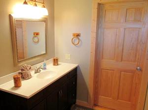 a bathroom with a sink and a mirror and a door at Magnificent Log Cabin with Mountain Views near Yellowstone National Park, Montana in Cliff Lake +16 photos