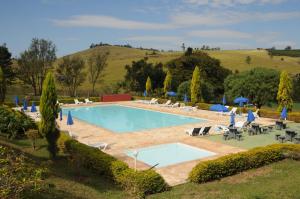 a swimming pool with lounge chairs and umbrellas at Hotel Fazenda Santa Maria in Serra Negra