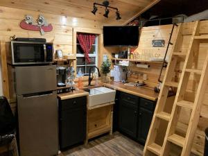 La cuisine est équipée d'un réfrigérateur et d'un évier. dans l'établissement Cozy Cabin near Kentucky Lake - Amazing Glamping Rental in Big Sandy, Tennessee, à Big Sandy