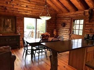 a dining room with a table and chairs in a cabin at Charming Log Cabin Getaway with Private Hot Tub near Decatur, Illinois in Larkdale +23 photos