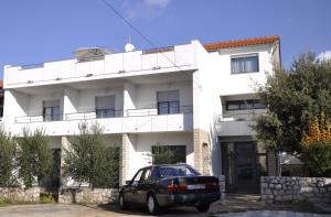 a white building with a car parked in front of it at Apartments Crobeg in Rab