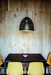 a dining room table with yellow chairs and a lamp at Luxurious Cabin Rental with a Hot Tub near Maribor for Glamping in Slovenia in Brestrnica