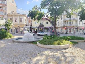 a street with a fountain in the middle of a city at Good Mood Apartments & Parking 2 in Plovdiv