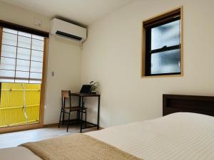 a bedroom with a bed and a desk and a window at Mulan Stay 松尾大社 in Kyoto