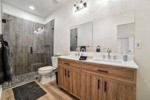 Un baño con lavabo, inodoro y ducha. en Three Stylish A-Frames Perfect for a Group Escape in Texas, en Fourth Crossing