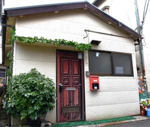 a small white house with a red door at Yui HOSTEL in Tokyo