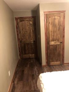 an empty room with two wooden doors and wooden floors at Amazing Cabin Rental near Ouachita National Forest for Weekend Getaways in Oklahoma in Hodgen