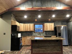 a kitchen with wooden cabinets and a sink and a refrigerator at Amazing Cabin Rental near Ouachita National Forest for Weekend Getaways in Oklahoma in Hodgen