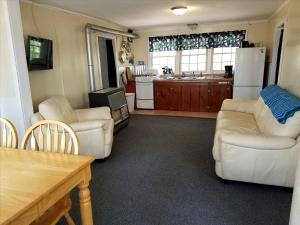 Il comprend un salon avec un mobilier blanc et une cuisine. dans l'établissement Charming Vacation Cabin with Waterfront Views on Pine Lake, Michigan, à Wellston