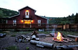 a woman sitting around a fire in front of a house at Luxurious Pet-Friendly Vacation Rental close to Mirror Lake in Kamas, Utah in Kamas