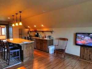 eine Küche mit einem TV und einem Tisch mit Stühlen in der Unterkunft Deluxe Getaway Rental in a Mountain Cabin near Lake McDonald, Montana in West Glacier