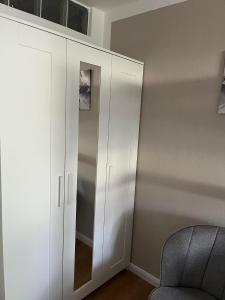 a white cabinet in a room with a chair at BergHerz Allgaeu in Sonthofen