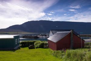 a red barn and a house with a mountain in the background at Fjord Guesthouse in Súðavík