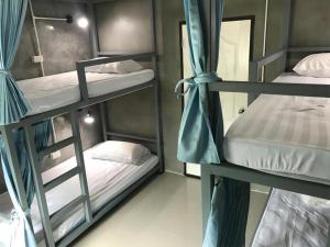 a room with three bunk beds in a hostel at Chomjan Hostel in Ko Phayam