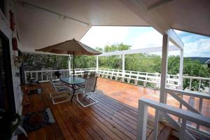 una terrazza in legno con tavolo e ombrellone di Riverfront Cabin with Spacious Interior, Large Deck and Views in Texas a Wimberley