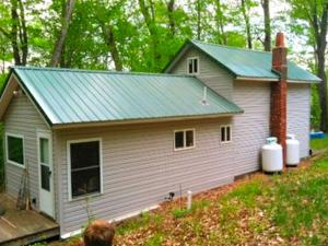 une petite maison blanche avec un toit vert dans l'établissement Rustic and Cozy Cabin Rental near Cherry Springs State Park, Pennsylvania, à Short Run