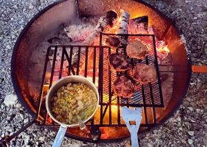a grill with meat and vegetables and a bowl of corn at Rustic Container Accommodation for Glamping in Kentucky in Owenton