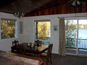 une salle à manger avec une table, des chaises et des fenêtres dans l'établissement Inviting Cabin Getaway on a Private Lake on the Kenai Peninsula, Alaska, à Kasilof