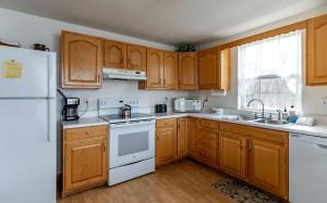 a kitchen with wooden cabinets and a white refrigerator at Secluded Lakefront Cabin with Private Dock on Lake Nantahala, Topton, North Carolina in Aquone