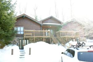 a log cabin in the snow with a car parked in front at Rustic Cabin Rental near the Ski Slopes in Snowshoe, West Virginia in Snowshoe