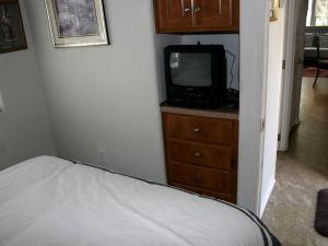 ein Schlafzimmer mit einem Bett und einem Fernseher auf einer Kommode in der Unterkunft Cozy Cottage Rental for Eight with Lake Views in New Braunfels, Texas in Schumannsville