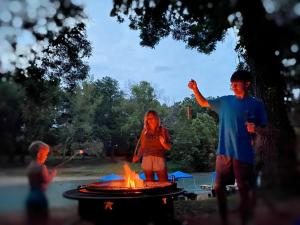a man and a woman standing next to a fire at Fantastic Safari Tent on the San Marcos River - Perfect for a Glamping Getaway near Kingsbury, Texas in Staples