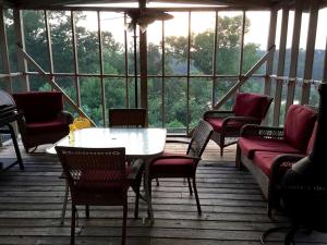 eine abgeschirmte Veranda mit einem Tisch und Stühlen in der Unterkunft Spacious Cottage with Pool for an Exciting Getaway on Smith Lake in Alabama in Brushy Pond