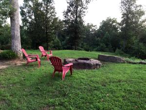 trois chaises roses assises dans l'herbe dans un champ dans l'établissement Spacious Cottage with Pool for an Exciting Getaway on Smith Lake in Alabama, à Brushy Pond 8 autres photos