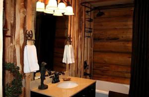 La salle de bains est pourvue d'un lavabo et d'un mur en bois. dans l'établissement Luxury Cabin with a Hot Tub near Yellowstone Park in Montana, à Nye
