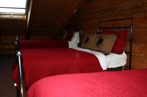 - une chambre avec 2 lits dotés de draps rouges et blancs dans l'établissement Luxury Cabin with a Hot Tub near Yellowstone Park in Montana, à Nye 1 autre photo