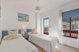 Un dormitorio con dos camas y una ventana. en Orion Beach, en Puerto