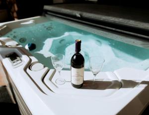 a bottle of wine and two wine glasses in a hot tub at Cozy Secluded Cabin with Games and Hot-tub in Sarahsville, Ohio in Senecaville