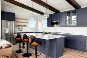 a kitchen with blue cabinets and a sink and stools at Scenic Getaway Cabin w/ Fire Pit, Deck & Panoramic Views in Martinsburg, WV in Martinsburg