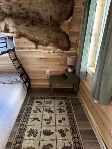 a bedroom with a bed and a table and a rug at Magnificent Cabin Nestled Amidst Trees in Portage Lake, Maine in Portage Lake Municipal Seaplane Base