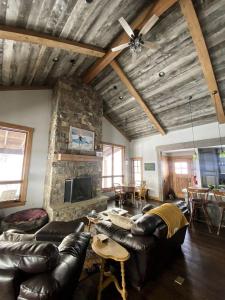 a living room with leather furniture and a stone wall at Charming Historic-Inspired Vacation Home with Mountain Views near Pony School House in Pony, Montana in Pony