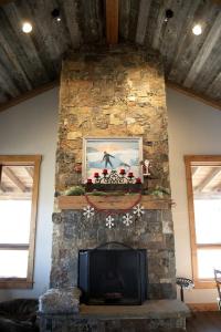 a stone fireplace in a living room with a tv at Charming Historic-Inspired Vacation Home with Mountain Views near Pony School House in Pony, Montana in Pony