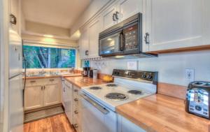 une cuisine avec des armoires blanches et un four à plaques de cuisson dans l'établissement Waterfront Cottage Rental with Spectacular Sunset Views on Orcas Island, Washington, à Deer Harbor