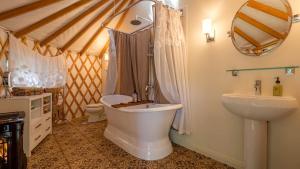 a bathroom with a tub and a toilet and a sink at Chic Woodland Yurt Rental on a Wellness Ranch in Southern California in Cayucos