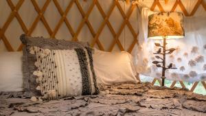 a bed with pillows and a lamp in a room at Chic Woodland Yurt Rental on a Wellness Ranch in Southern California in Cayucos