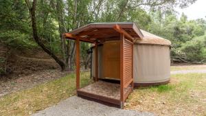 a outhouse with a wooden roof in a park at Chic Woodland Yurt Rental on a Wellness Ranch in Southern California in Cayucos +13 photos
