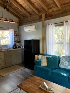 a living room with a blue couch and a kitchen at Tranquil Glamping near the Coast: Charming Rustic Cabin Rental in Midway, Georgia in Fancy Hall