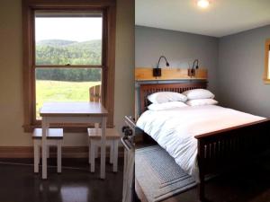 a bedroom with a bed and a table and a window at Elegant Cabin Rental on a Hillside Farm in Hartland, Vermont in Sheddsville