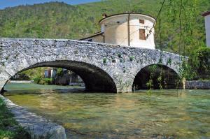 a stone bridge over a river with a building at Apartment Thomas in Vipava