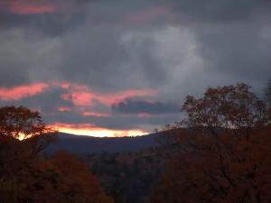 una puesta de sol en las montañas con árboles en primer plano en Romantic Getaway Cabin on a Working Farm in Royalton, Vermont, en South Royalton