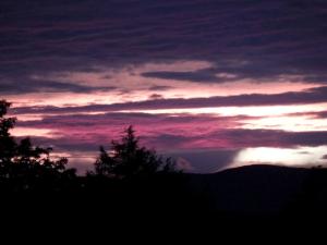 Una puesta de sol en el cielo con árboles en primer plano. en Romantic Getaway Cabin on a Working Farm in Royalton, Vermont, en South Royalton