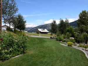 un jardin avec une pelouse et des montagnes en arrière-plan dans l'établissement Charming Vacation Rental for Large Groups near Yellowstone National Park, Wyoming, à Thayne